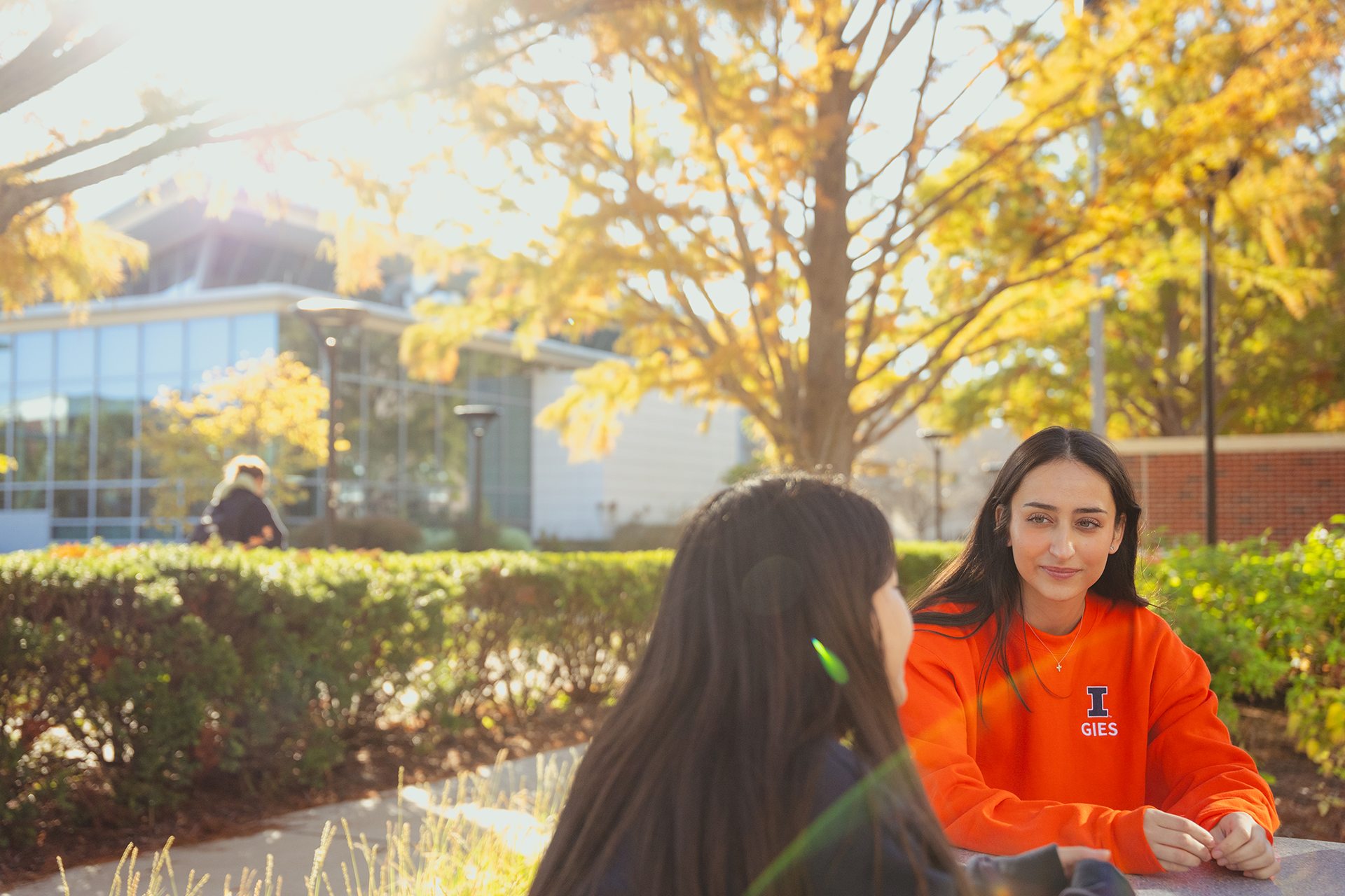 Two students sitting outside Wymer Hall in the fall