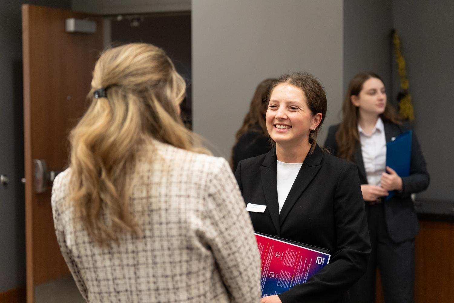 Student in black suit smiling at career fair