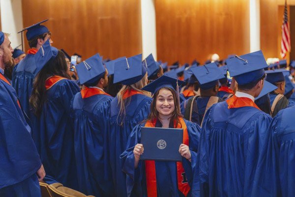 Gies Business student at graduation holding diploma