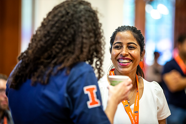 Two women talking and smiling while holding coffee Two women talking and smiling while holding coffee