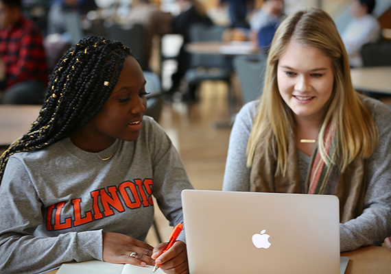 Undergraduate Admissions ICT Two female students share a laptop and work on a project in the Business Instructional Facility commons area.